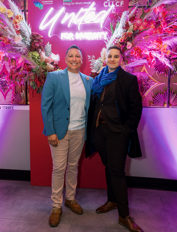 Two people with a neon sign behind them at a Givher event