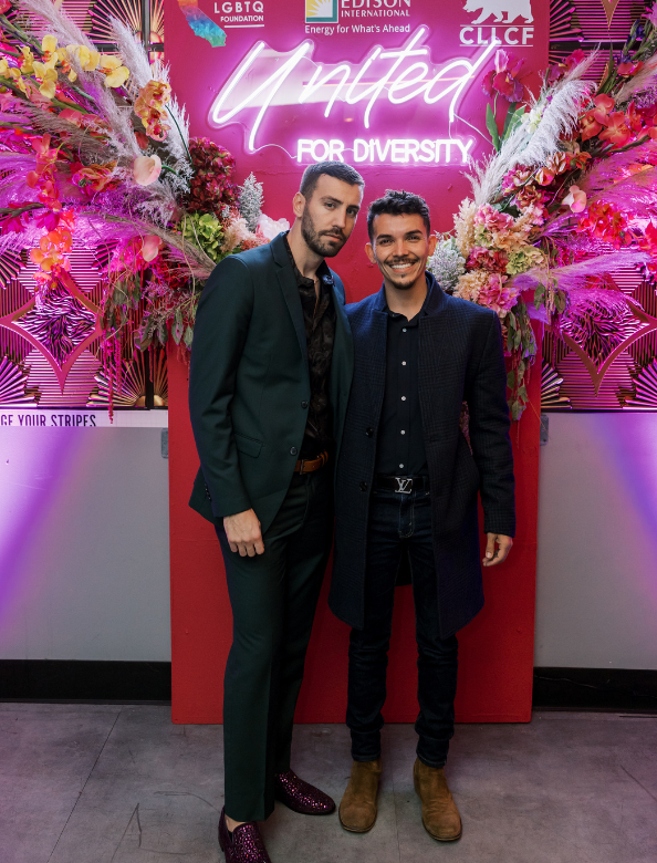 Two people with a neon sign behind them at a Givher event